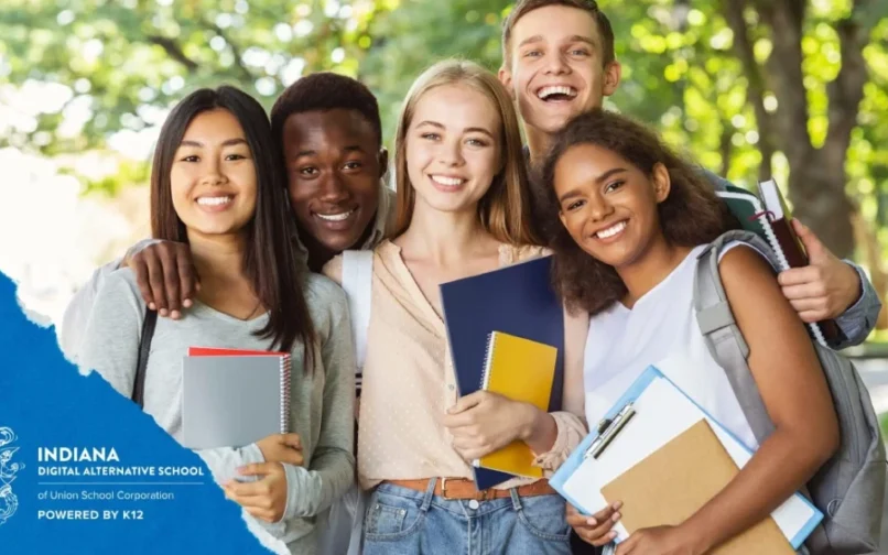 A diverse group of five smiling students holding notebooks and backpacks, standing outdoors in a park-like setting. The image conveys friendliness and camaraderie.