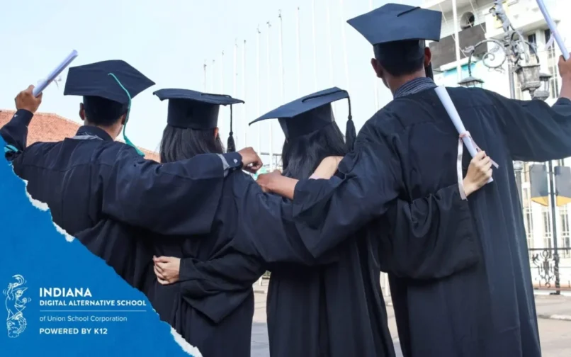 Five graduates in black gowns and caps, their backs to the camera, link arms while holding diplomas. The mood is celebratory and joyful.